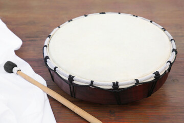 Modern drum with drumstick on wooden table