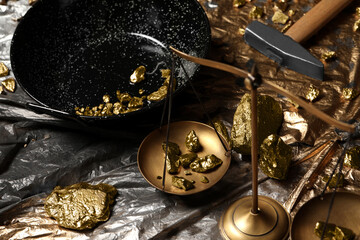 Gold nuggets, vintage scales, hammer and wok on plastic stretch wrap