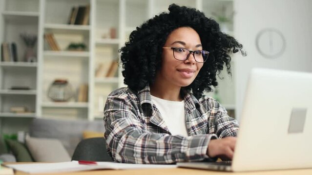 Portrait of young african american woman student looking at laptop computer screen with nod of approval and looking at camera with thumbs up at home Advise Approve Recommend Choice concept