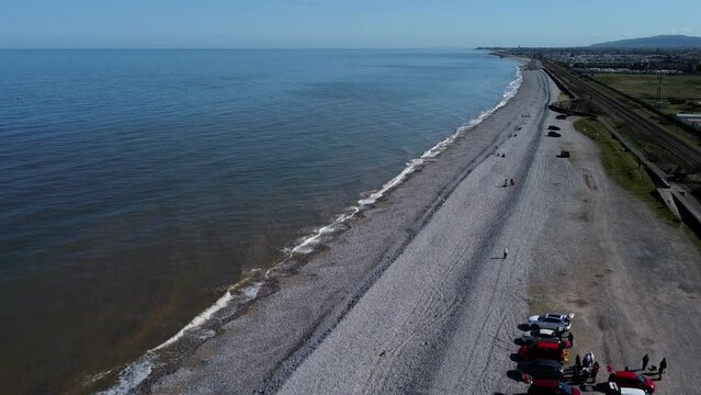 Aerial view Pensarn sunny pebble beach and ocean waves looking down to Rhyl town on the distant horizon