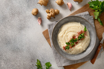 Vegan Jerusalem artichoke puree decorated parsley on gray background. View from above. Copy space.