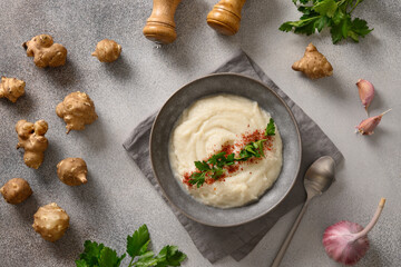 Vegan Jerusalem artichoke puree in plate decorated parsley on gray background. View from above.