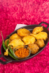 Indian Tea time snacks in group includes Veg Samosa, Kachori/kachaudi, aloo bonda, khaman dhokla, bread, onion,chilli and moong pakora/pakoda/bhaji/bhajji/Bhajiya/bajji with sauces, selective focus