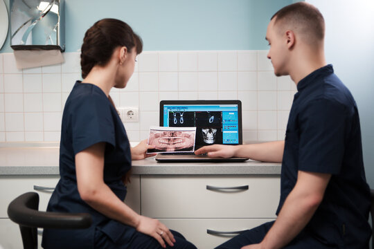 Doctors dentists analyzes X-ray of the patient's jaw on a laptop screen.	