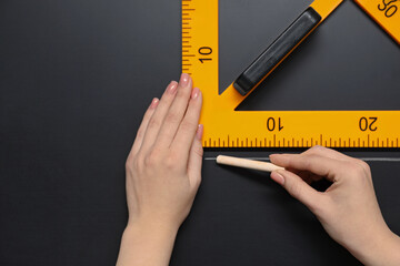 Woman drawing with chalk and triangle ruler on blackboard, closeup. Space for text