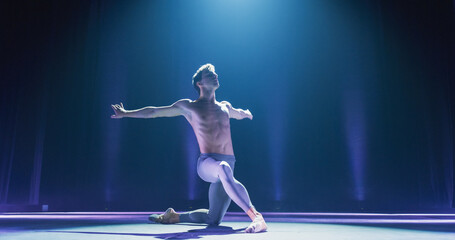 Wide Cinematic Shot of Athletic Man Dancing and Rehearsing on Classic Theatre Stage with Dramatic Lighting. Graceful Classical Ballet Male Dancer Performing his Choreography Professionally © Kitreel