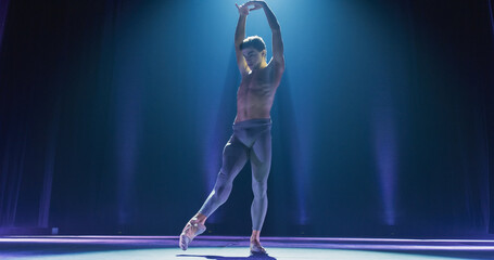 Wide Cinematic Shot of Athletic Man Dancing and Rehearsing Pirouettes on Classic Theatre Stage with Dramatic Lighting. Graceful Classical Ballet Male Dancer Performing his Choreography Professionally © Kitreel