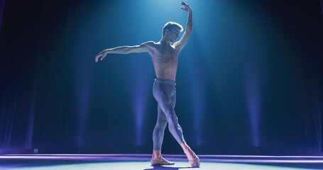 Wide Cinematic Shot of Athletic Man Dancing and Rehearsing Pirouettes on Classic Theatre Stage with Dramatic Lighting. Graceful Classical Ballet Male Dancer Performing his Choreography Professionally © Kitreel