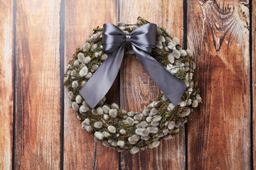 Wreath made of beautiful willow branches and grey bow on wooden background, top view © New Africa