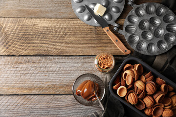 Making walnut shaped cookies. Cooked dough, mold, boiled condensed milk and nuts on wooden table, flat lay. Space for text