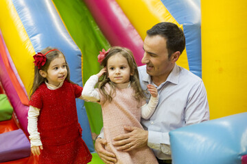 Ritratto di un papà con le figlie gemelle di tre anni.