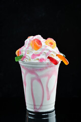 Strawberry milkshake in a plastic cup. on a black background. Free space for text.