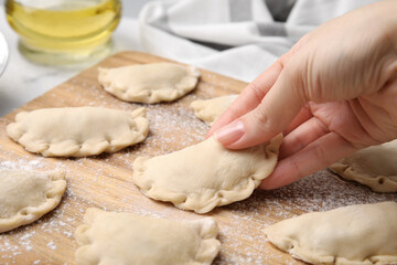 Woman making dumplings (varenyky) with tasty filling at table, closeup