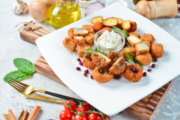 Fondue. Fondue with cheese, mushrooms and vegetables. On a white plate. On a gray stone background. Restaurant menu.