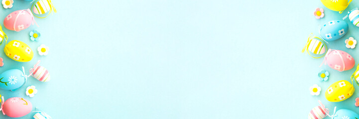 Easter background on blue. Eggs, spring leaves, flowers and colored butterflies. Long banner format flat lay.