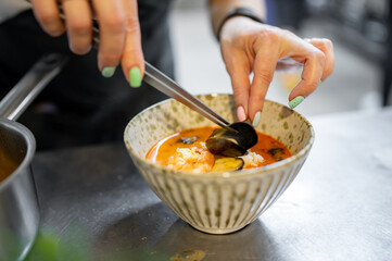 woman chef cooking seafood soup on restaurant kitchen