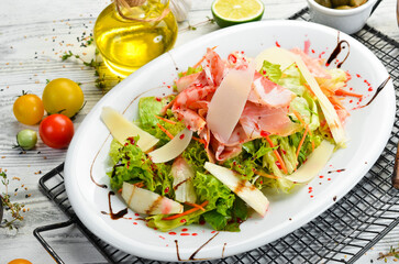 Salad with prosciutto, cheese, pear and herbs. Top view. Rustic style.