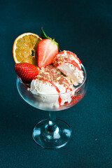 Sweet creamy ice cream with strawberries in a glass cup. Dessert. On a dark background, close-up.