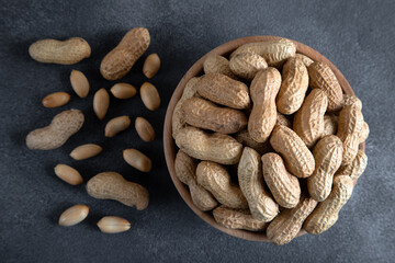 Bowl full of shelled and roasted peeled peanuts on black  background,top view
