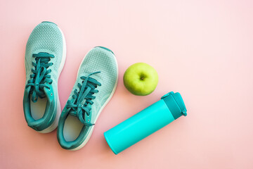 Workout and healthy lifestyle concept. Sneakers, green apple and bottle of water. Flat lay with copy space.