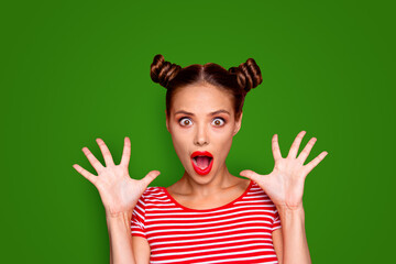 Closeup portrait of shocked girl with brown eyes and red lipstick on the mouse look at the camera with his fingers spread wide. Concept of advertising isolated on red background