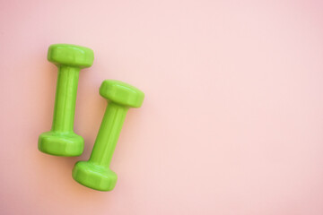 Green Dumbbells on pink. Flat lay image with copy space.