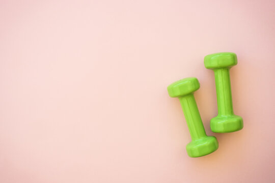 Green Dumbbells on pink. Flat lay image with copy space.