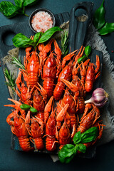 Crayfish. Red boiled crawfishes in a bowl with rosemary and spices. On a dark background. Free space for the recipe.