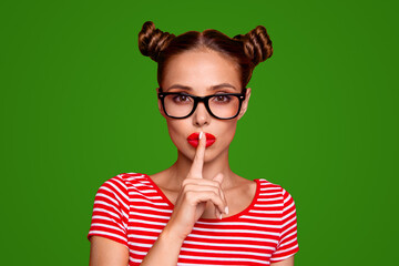 Shh Portrait of attractive mysterious girl in glasses gesturing silence sign with forefinger red pout lips looking at camera isolated on red background - obrazy, fototapety, plakaty