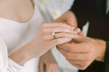 Gentle photo of the groom putting on the ring to the bride. Newlyweds