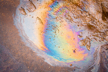 Tire tracks in the melting snow against the background of an oil spot on asphalt road