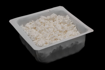 Cottage cheese in container isolated on black background. Nutty-flavored dairy curds. Side view