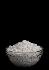 Cottage cheese in glass bowl isolated on black background. Side view of High-protein dairy snack