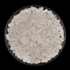 Cottage cheese in glass bowl isolated on black background. Top view of Nutritious milk product