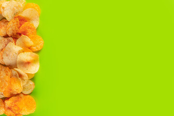 Border of potato chips isolated on vibrant light green background. Light and crispy chip that is...