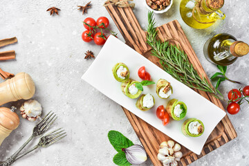 Zucchini rolls with feta cheese. On a white plate. On a gray stone background. Restaurant menu.