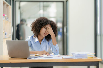 African businesswoman stressed and headache with paperwork tired suffering from temporal temporal...