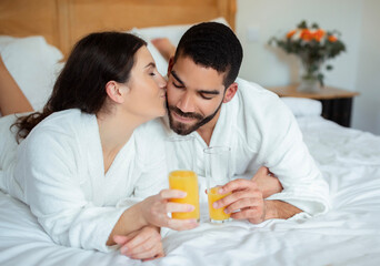 Wife Kissing Husband's Cheek Drinking Juice Relaxing In Hotel Room