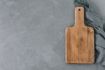 Chopping board. Empty wooden cutting board with napkin on gray stone background