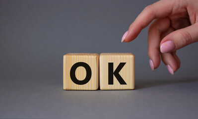 Ok symbol. Concept word Ok on wooden cubes. Businessman hand. Beautiful grey background. Business and Ok concept. Copy space.