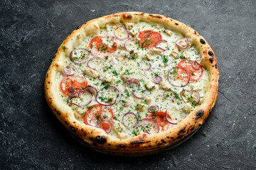 Traditional pizza with chicken, tomatoes and cheese. Takeaway food. On a black stone background. Rustic style.