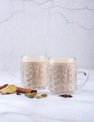 Two glass mugs with masala tea and spices.