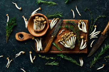 Brown beech mushrooms or Shimeji mushroom on a wooden kitchen board. on a black stone table. Top view.