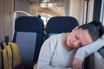 Woman sleeping in a train seat while travelling.