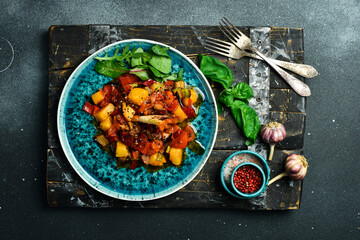Stewed veal with pumpkin and vegetables on a plate. Close up. On a dark background.