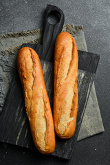 Fresh crispy baguette on a black slate table. Top view. Copy space.