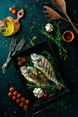 Grilled Dorado fish with spices and vegetables. On a black background. Photo for the menu.