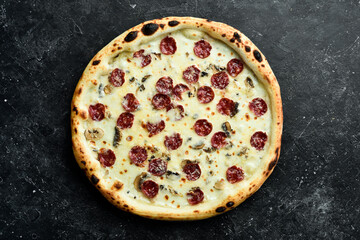 Pizza with Bavarian sausages and cheese. Top view. On a black stone background.
