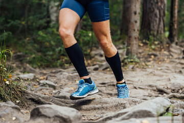 Fototapeta na wymiar legs runner in compression sleeves on his feet run forest trail race over stones, summer marathon race