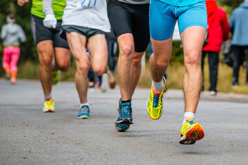 close-up legs group athletes runners running race on road, men jogging marathon